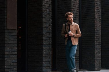 Kahve molası. Sakallı, haki renkli ceketli ve kot pantolonlu şık bir adam binanın yanında..