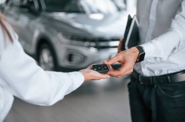 Yeni otomobilin anahtarları. Manzarayı kapat. Beyaz elbiseli bir adam araba galerisinde birlikte..