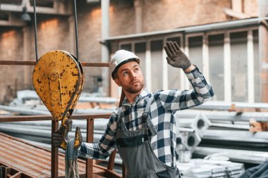 Vinç operatörüyle iletişim kur. Üniformalı fabrika çalışanı içeride..