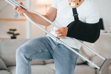 Ayakta duruyor, koltuk değneğini tutuyor ve gitar çalıyormuş gibi yapıyor. Eğleniyorum. Evdeki adam içeride. Yaralı..