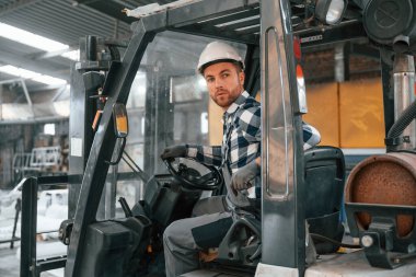 Forkliftin içinde. Üniformalı fabrika çalışanı içeride..
