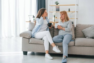 Bir bardak içkiyle, sohbet ederek. Anne ve kızı evde birlikteler..