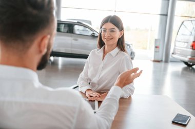 Bir anlaşma yapıyorum. Masanın yanında oturuyor. Beyaz elbiseli bir adam araba galerisinde birlikte..