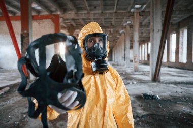 Solunum cihazını veriyorum. Kıyamet sonrası binanın harabelerinde kimyasal koruma kıyafeti giymiş bir adam..