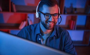 Okuma ve mavi neon ışıkları. Adam evde bilgisayarın başında oturuyor..