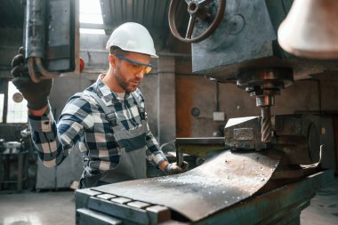 Otomatik matkabı çalıştırıyorum. Üniformalı fabrika çalışanı içeride..