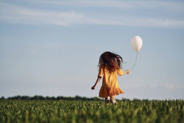 Elinde balonla koşuyor. Mutlu kız yazın dışarıda gezintiye çıkar..