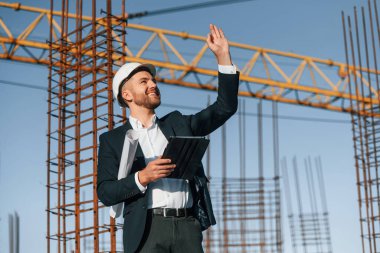 El hareketleriyle emirler veriyor. Resmi kıyafetli bir işadamı gün içinde şantiyede olacak..