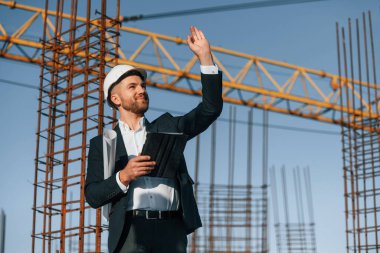 El hareketleriyle emirler veriyor. Resmi kıyafetli bir işadamı gün içinde şantiyede olacak..