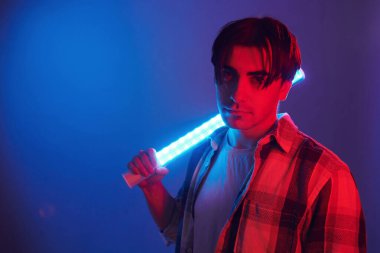 Holding lighting equipment. Man standing in the studio with neon.