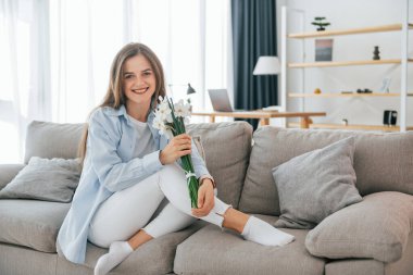 Güzel beyaz çiçekler ellerinde. Genç ve güzel bir kadın evde tek başına..