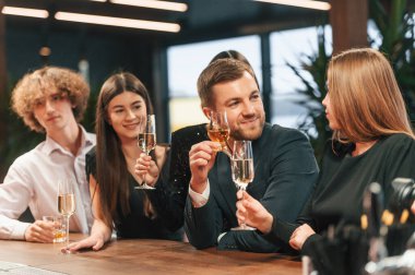 Arkadaşlar eğleniyor. Bir grup şık giyinmiş insan restoranda kutlama yapıyor..