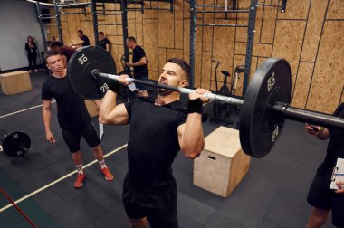 Elleriniz için alıştırma yapın. Güçlü adam spor salonunda halteri kaldırıyor..