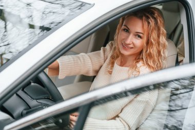 Kapı açıkken. Genç bayan arabada oturuyor..