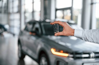 Otomobili uzaktan kumandayla kapatıyorum. Beyaz elbiseli genç adam araba galerisinde..