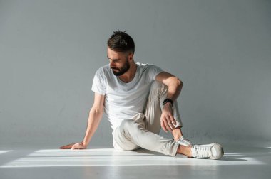 Yerde oturuyordum. Yakışıklı adam stüdyoda beyaz arka plana karşı..