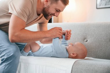 Yan görüş. Kanepeye uzanıyordu. Yeni doğmuş bebeğiyle baba içeride. Bekar baba kavramı.