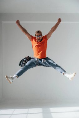 Mutlu adam zıplıyor, çığlık atıyor ve başarıyı kutluyor. Yakışıklı adam stüdyoda beyaz arka plana karşı..