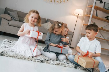 Hediye kutularını açıyorum. Doğum günü partisi. Bir grup çocuk gündüzleri evde birlikteler..