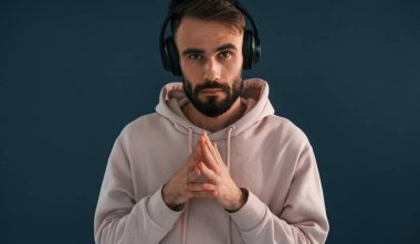 Kulaklıkla müzik dinlemek. Yakışıklı adam stüdyoda mavi arka planda..