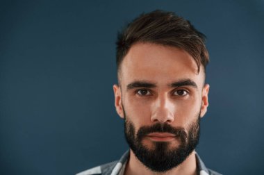 Portreyi kapat. Yakışıklı adam stüdyoda mavi arka planda..