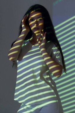 Yeşil renkli çizgiler. Stüdyoda projektör neon ışıkları altında güzel genç bir kadın var..