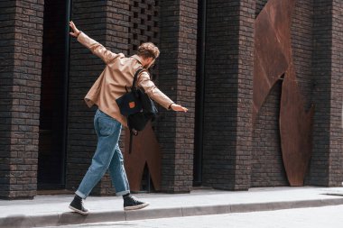 Kaldırımda yürürken eğleniyorum. Sakallı, haki renkli ceketli ve kot pantolonlu şık bir adam binanın yanında..