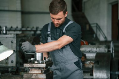 Metalle çalışmak. Üniformalı adam içeride tarım tekniğinin detaylarını geliştiriyor..