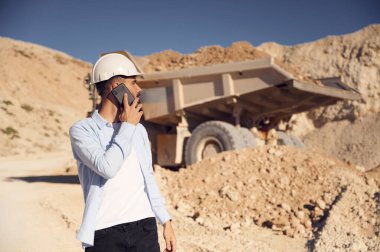 Telefonla iş görüşmesi. Üniformalı adam gündüz taş ocağında çalışıyor..