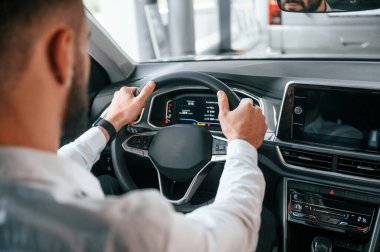 Test sürüşü. Beyaz elbiseli genç adam araba galerisinde..