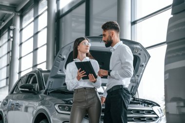 İleri yürüyüp konuşmak. Beyaz elbiseli bir adam araba galerisinde birlikte..