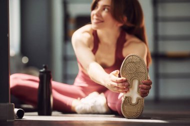 Tatbikata hazırlanıyorum. Esneme hareketleri yapıyorum. Spor elbiseli genç bir kadın spor salonunda spor yapıyor..