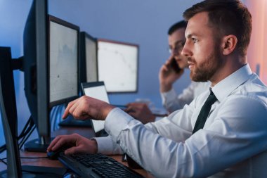 Yan görüş. Ofiste değişim teknolojisiyle çalışan iki borsacı..