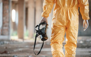 Solunum cihazı elinde. Kıyamet sonrası binanın harabelerinde kimyasal koruma kıyafeti giymiş bir adam..