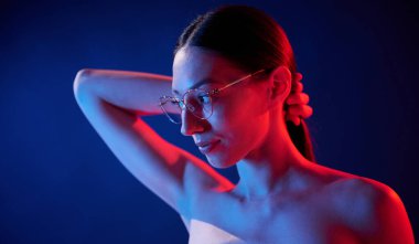 Gözlüklü, kötü görüş anlayışı. İçerideki neon ışıkta duran genç bir kadının portresi..