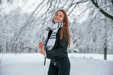 Sıcak eşarbın içinde. Güzel genç bir kadın kış ormanında dışarıda..