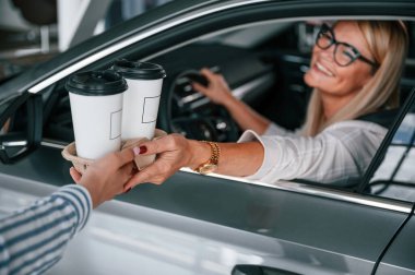 Bir bardak içki içiyorum. Beyaz elbiseli kadın araba galerisinde..