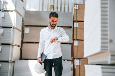 Resmi kıyafetlerle. Depo işçisi depoda bir sürü ürünle birlikte..