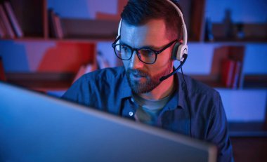 Okuma ve mavi neon ışıkları. Adam evde bilgisayarın başında oturuyor..