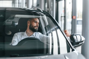 Ön manzara. Otomobilin içinde oturuyor. Beyaz elbiseli genç adam araba galerisinde..