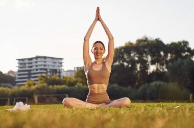 Yoga egzersizleri yapıyorum. Yoga elbiseli genç bayan dışarıda, sahada..