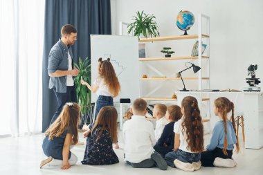 Tahtaya yazıyorum. Okulda öğretmenle birlikte bir grup çocuk öğrenci..