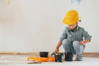 Yere yatın! Küçük çocuk ev odasında duvarları boyuyor..