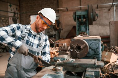 Koruyucu gözlüklü ve kasklı. Üniformalı fabrika çalışanı içeride..