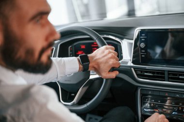 Test sürüşü. Beyaz elbiseli genç adam araba galerisinde..