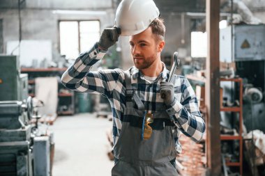 Yapay ışıklandırmayla depoda dikiliyorum. Üniformalı fabrika çalışanı içeride..