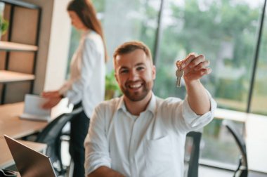 Yeni dairenin anahtarlarını saklıyorum. Erkek ve kadın modern ofiste birlikte çalışıyorlar..