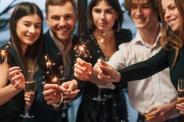 Yeni yıl maytaplarıyla. Güzel ve şık giyinmiş bir grup insan içeride birlikte..