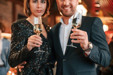 Çift poz veriyor. Güzel giyinmiş bir grup insan içeride yeni yılı kutluyorlar..