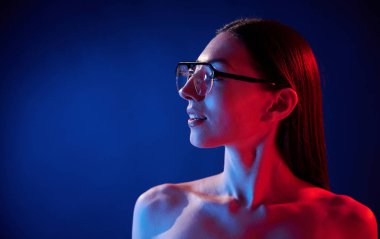 Göz giysisiyle. İçerideki neon ışıkta duran genç bir kadının portresi..